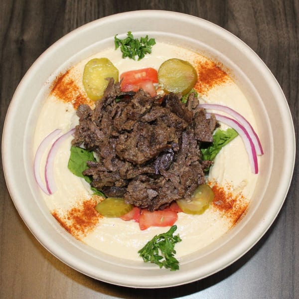 Baba Dari Mediterranean Grill's hummus bowl with shawarma, pickles, tomatoes, red onions, and parsley.