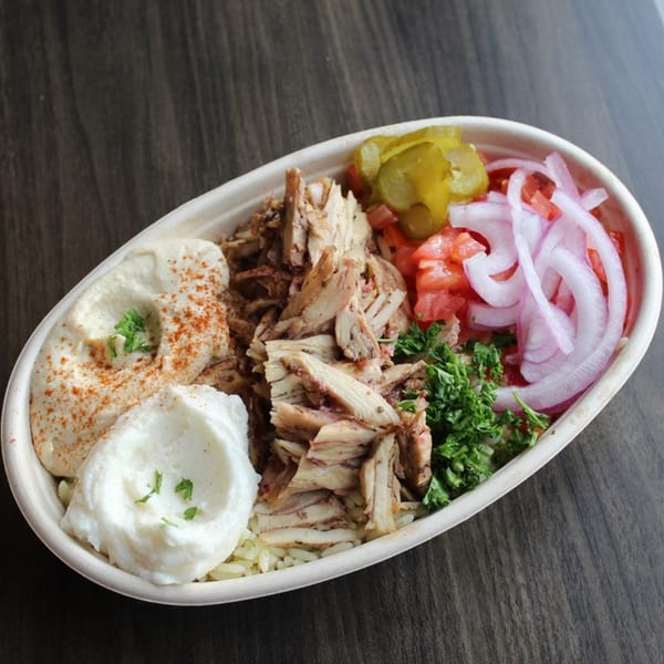 Baba Dari Mediterranean Grill's chicken shawarma bowl with hummus, garlic sauce, rice, pickles, tomatoes, onions, and parsley.